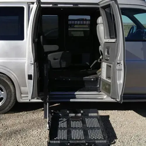 Silver van with open side door and deployed wheelchair ramp.