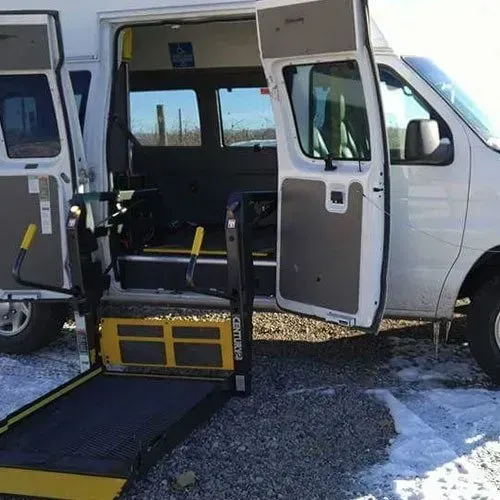 White accessible van with ramp extended, doors open.