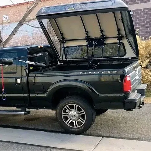 Black truck with a canopy. Canopy is open, revealing the bed. 