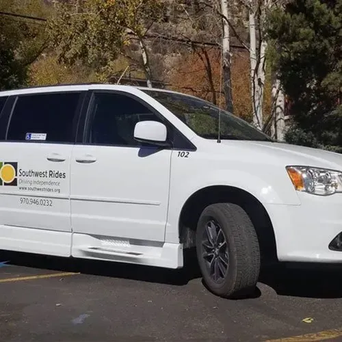 White Southwest Rides van with accessibility features parked outdoors.