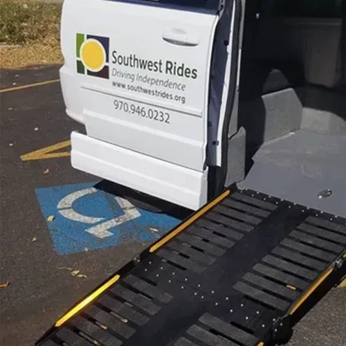 White Southwest Rides van with ramp extended at a designated handicap parking space.
