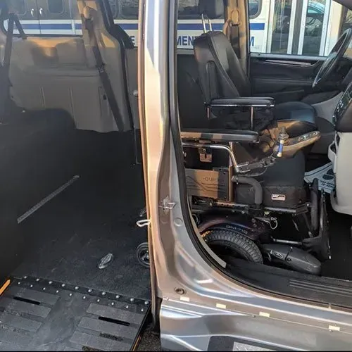 Interior of accessible van. Wheelchair ramp deployed. Driver's seat and wheelchair visible.