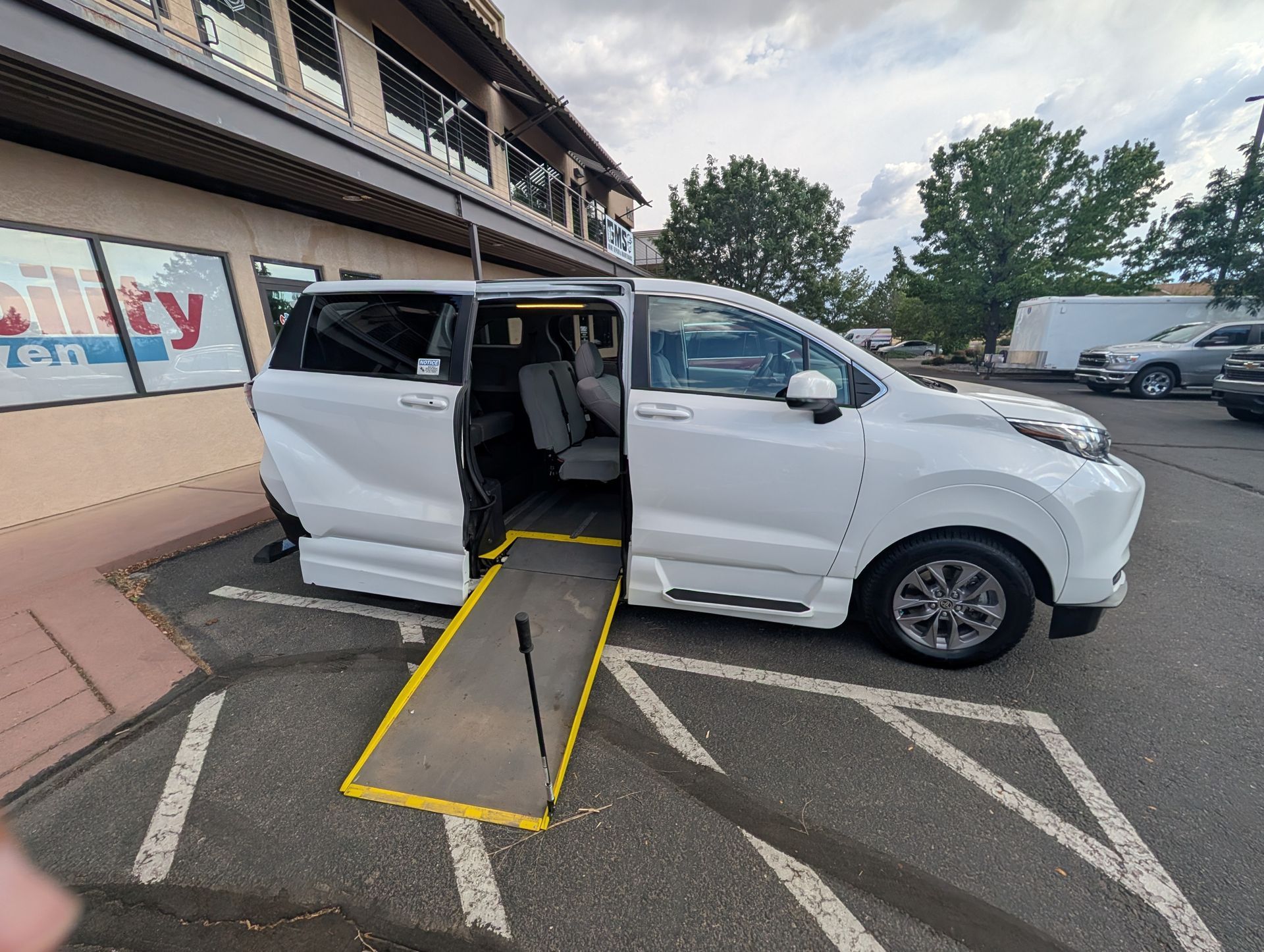 White wheelchair-accessible van with side ramp deployed in a parking lot