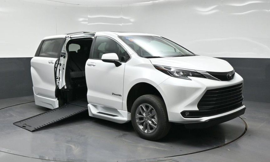 White minivan with side door open on a studio turntable, showing wheelchair ramp access.