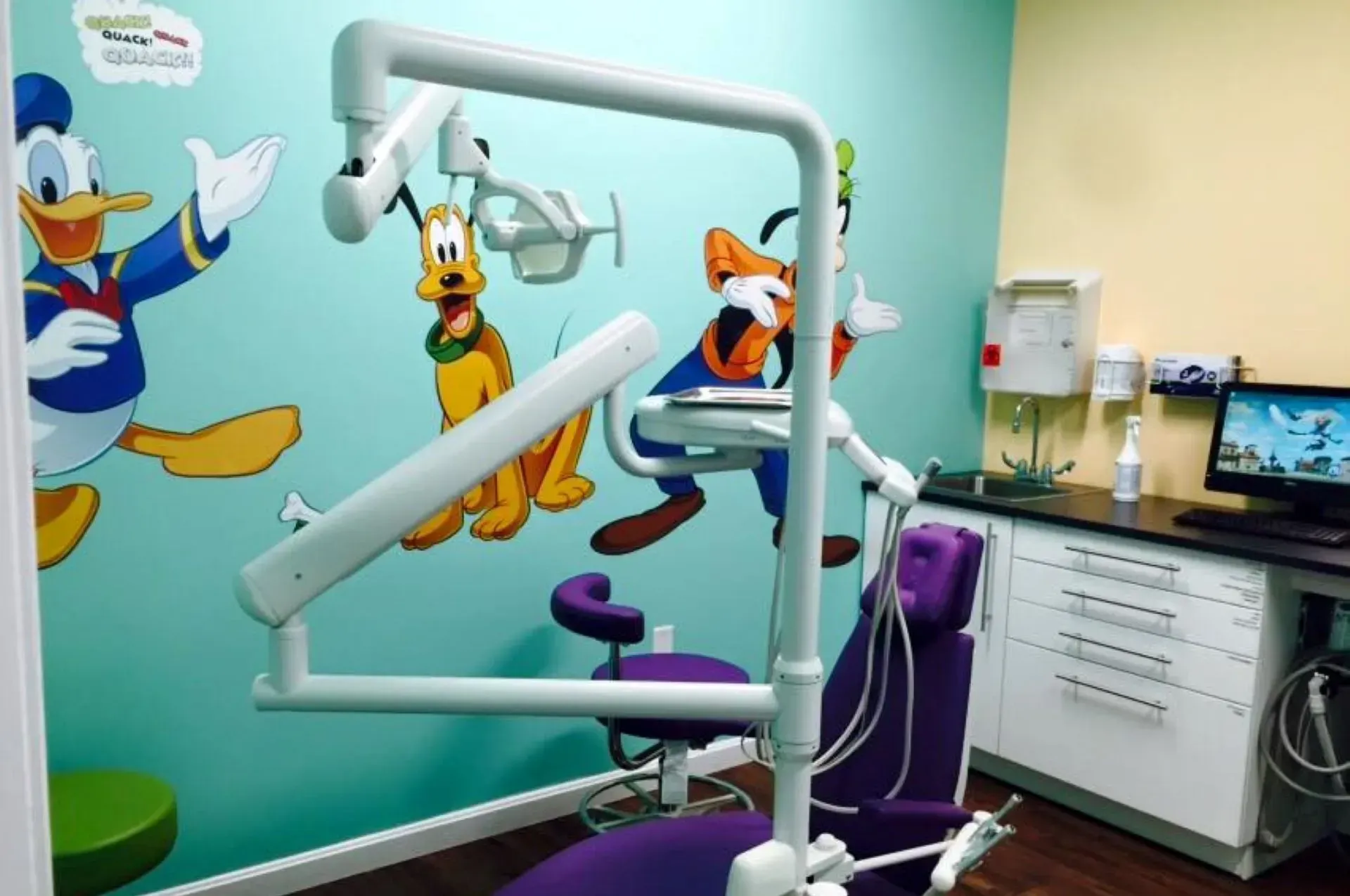 Child reclining in a dental chair while a dentist examines teeth with blue-gloved hands