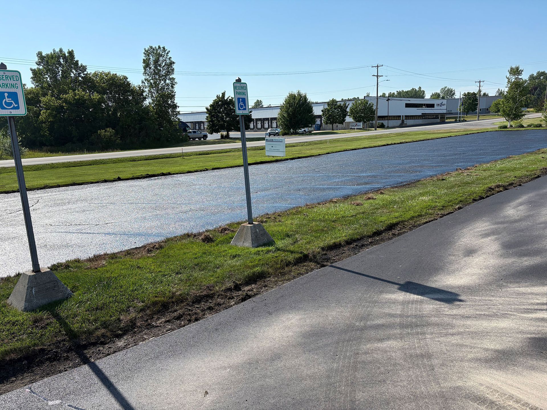 A handicapped parking sign is on the side of a road next to a body of water.