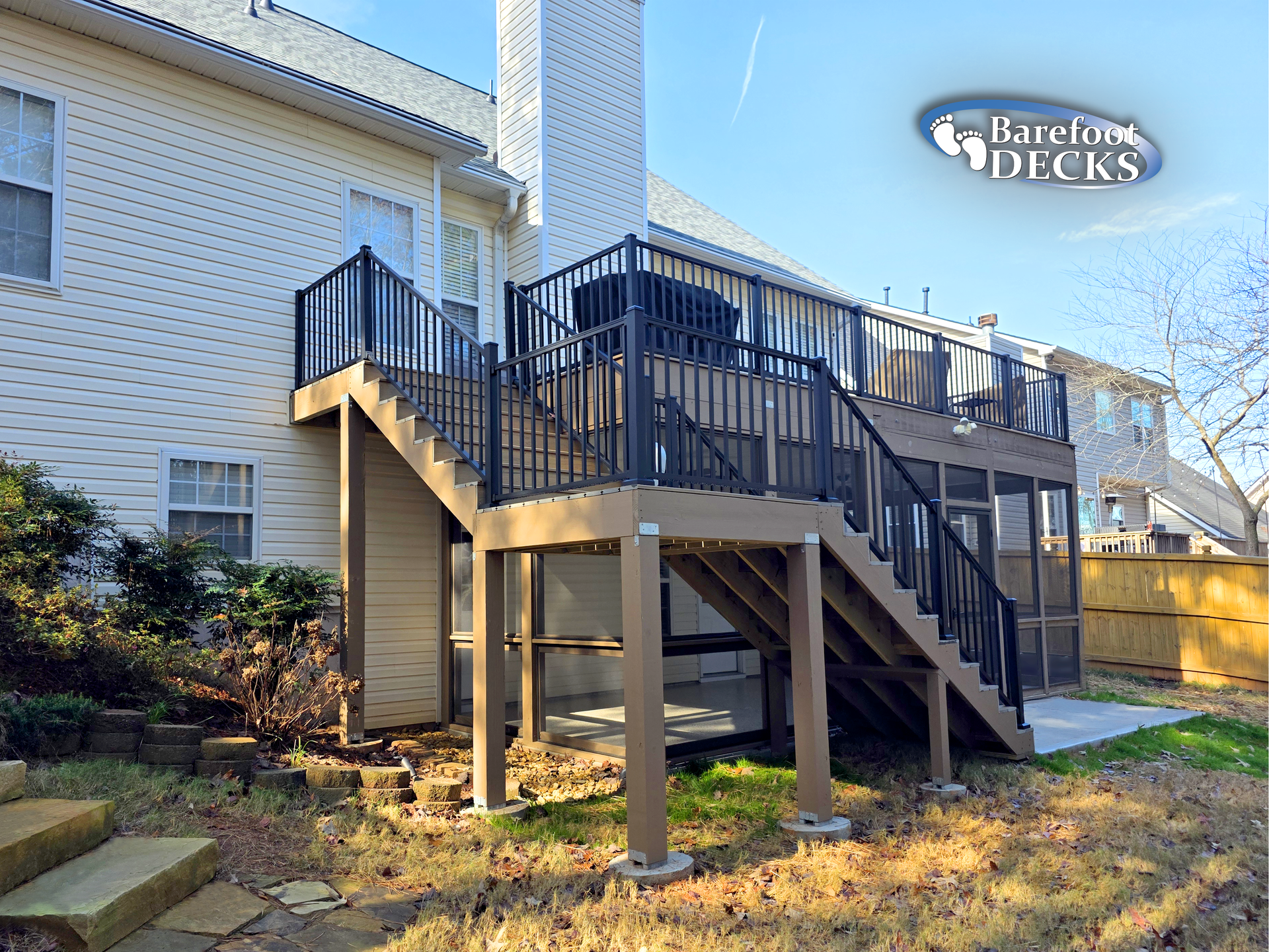 Back deck with black railings and stairs attached to a white brick townhouse