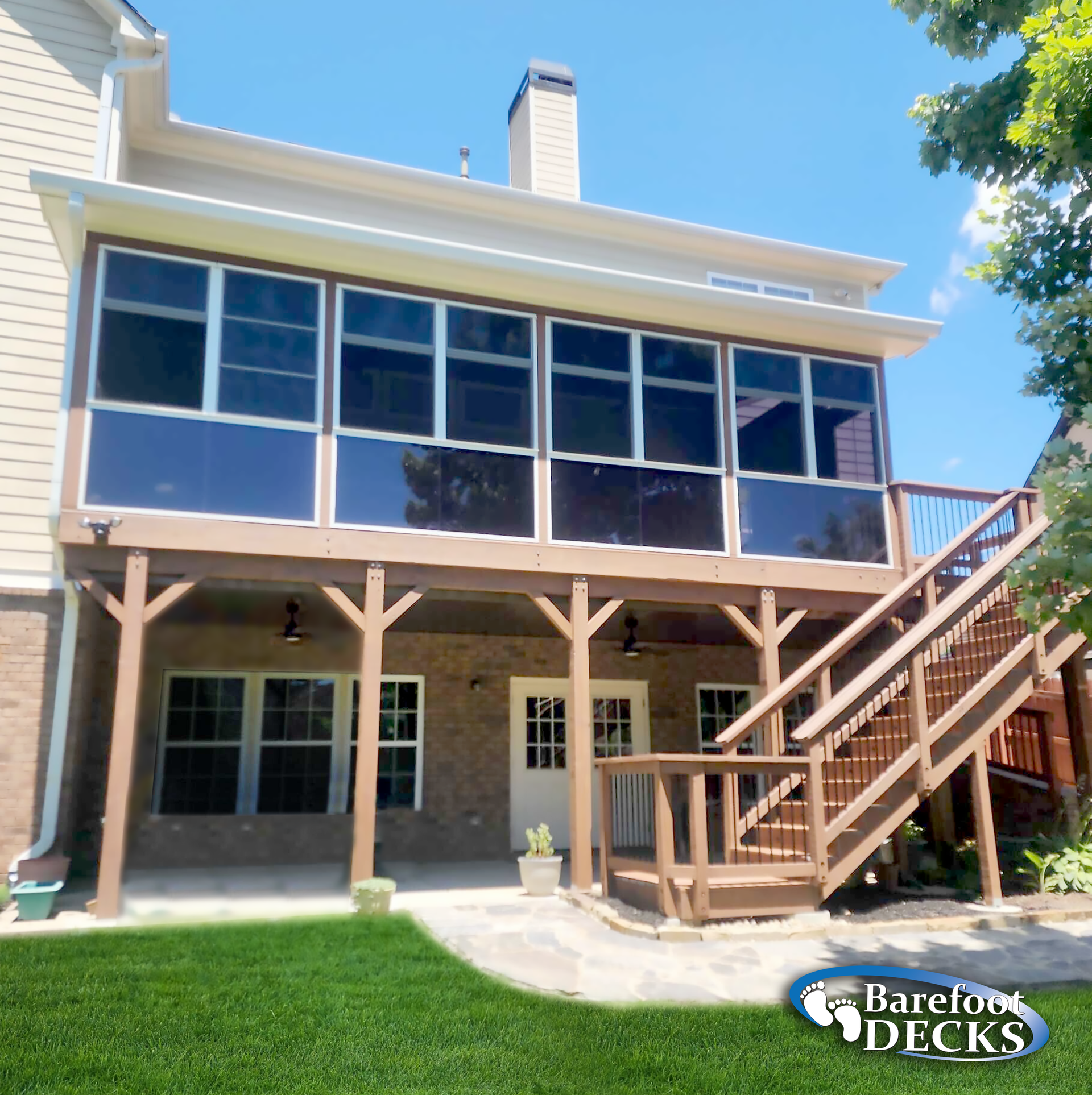Two-story deck with screened-in porch and stairs, attached to a brick home.