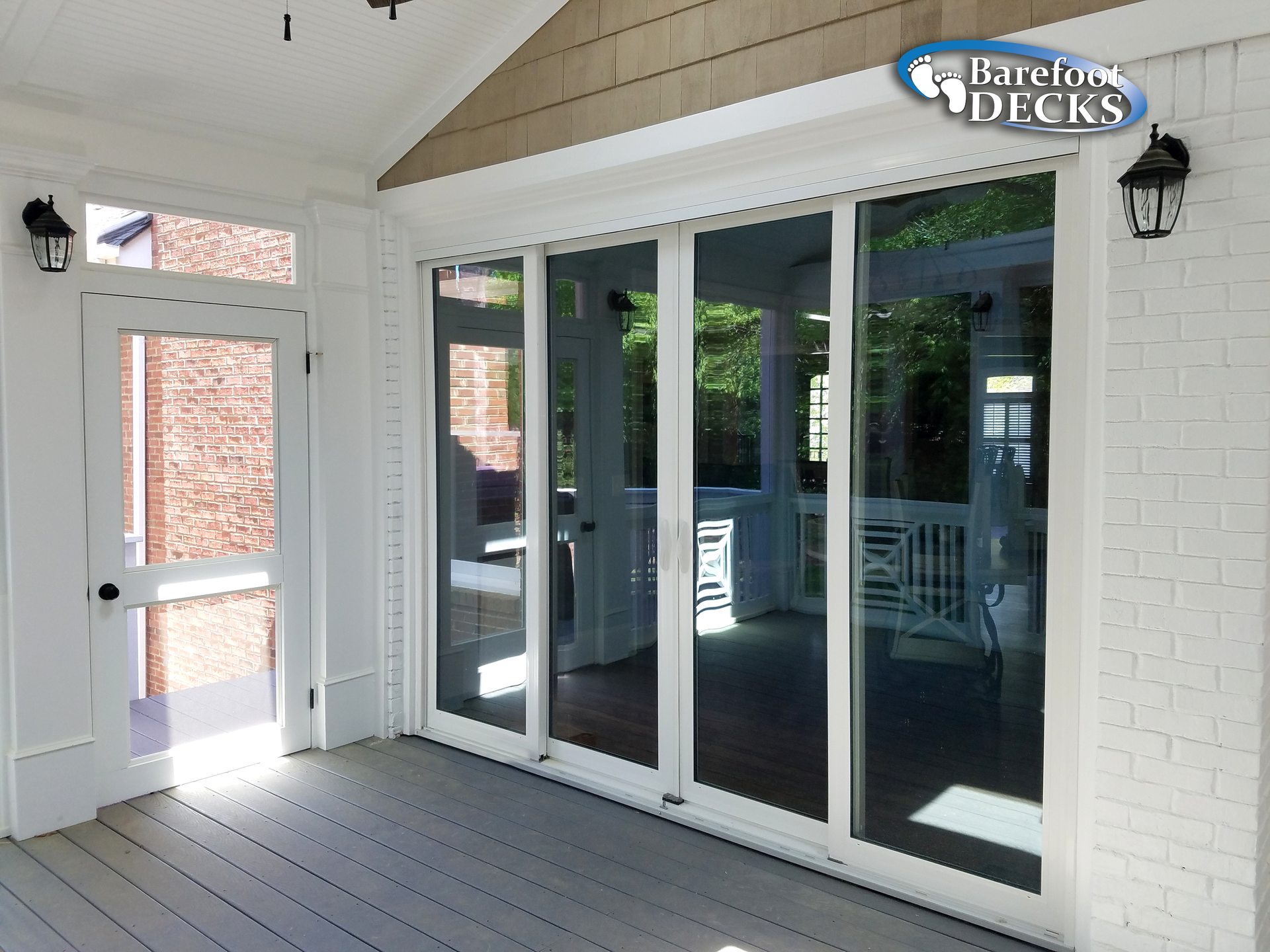 Sunroom with sliding glass doors, white trim, brick wall, and outdoor lanterns.