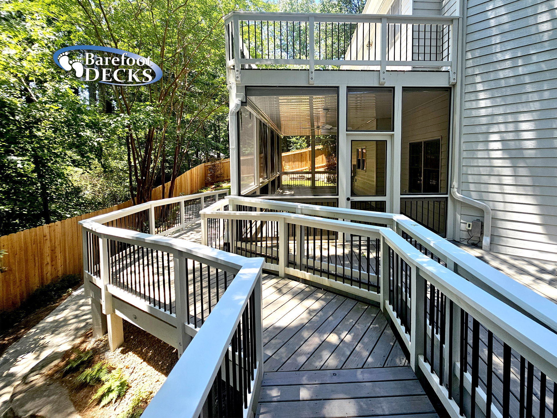 Wooden deck with ramp and railing leading to screened-in porch, attached to a house.