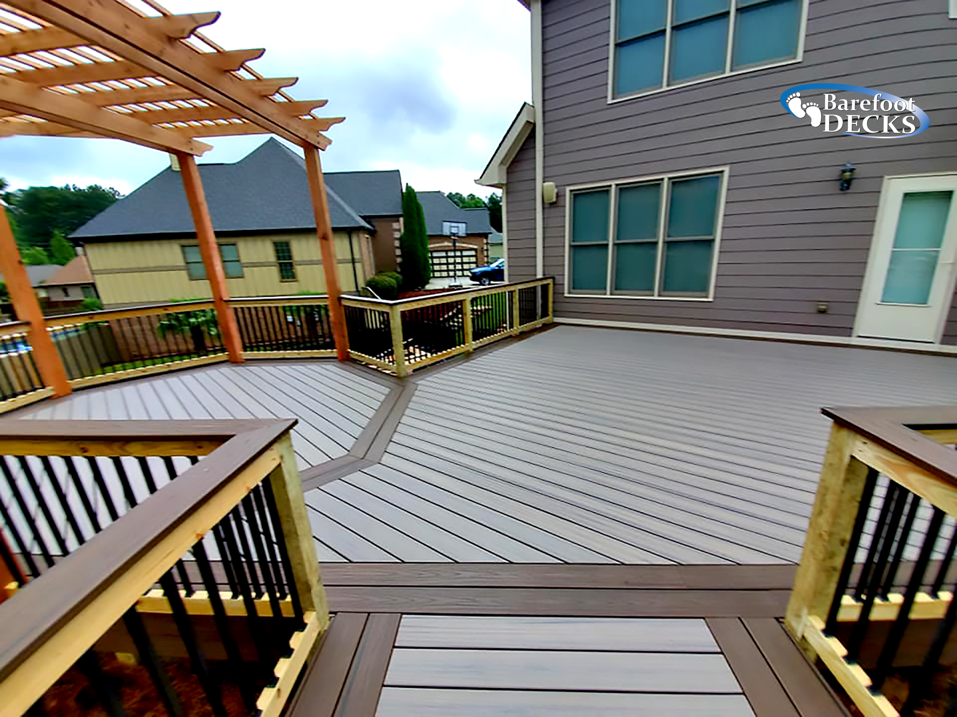 Composite deck with pergola, stairs, and house. Gray decking, brown trim, and wooden accents.