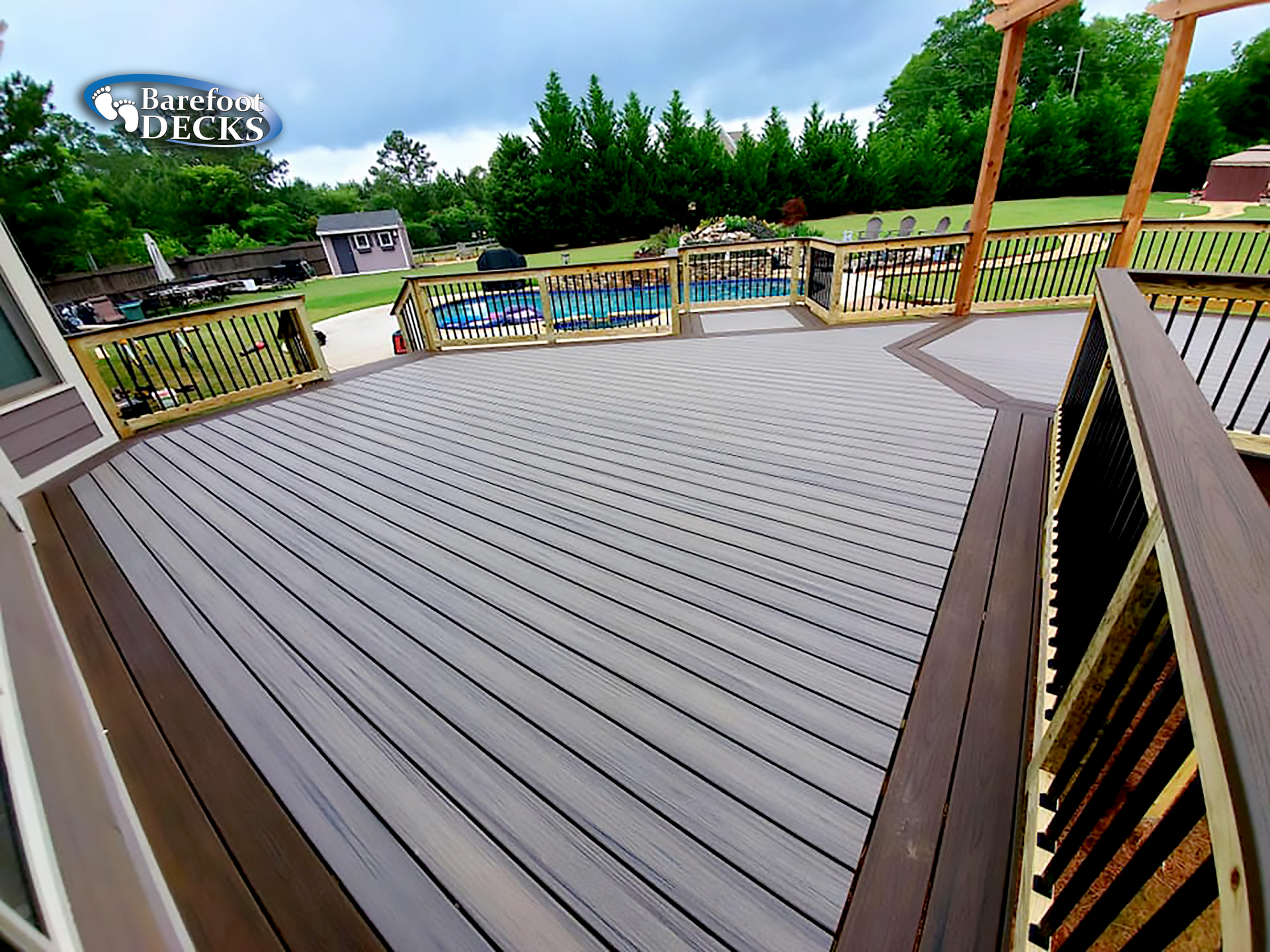 Composite deck with multiple levels, gray and brown tones, overlooking a backyard with trees.