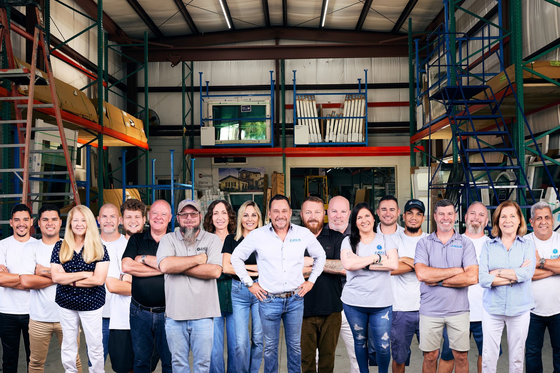 Group of people standing in a warehouse, posing with arms crossed in front of industrial shelving