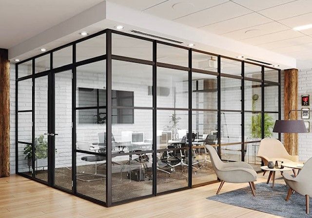 Modern office space with glass-walled conference room, visible interior, and lounge area with seating.