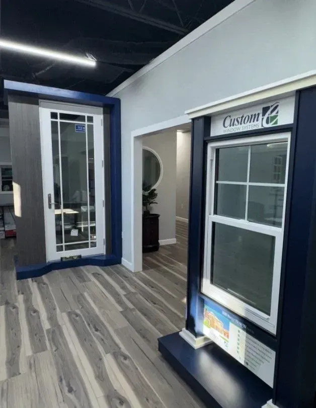 Window display room with a door and a double-hung window framed in dark blue. Gray wood-look floor.