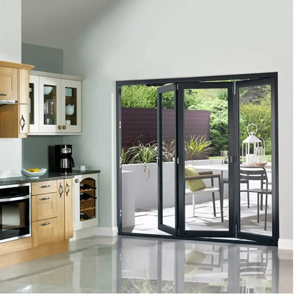 Kitchen with open dark-framed folding doors leading to a patio with table and chairs.