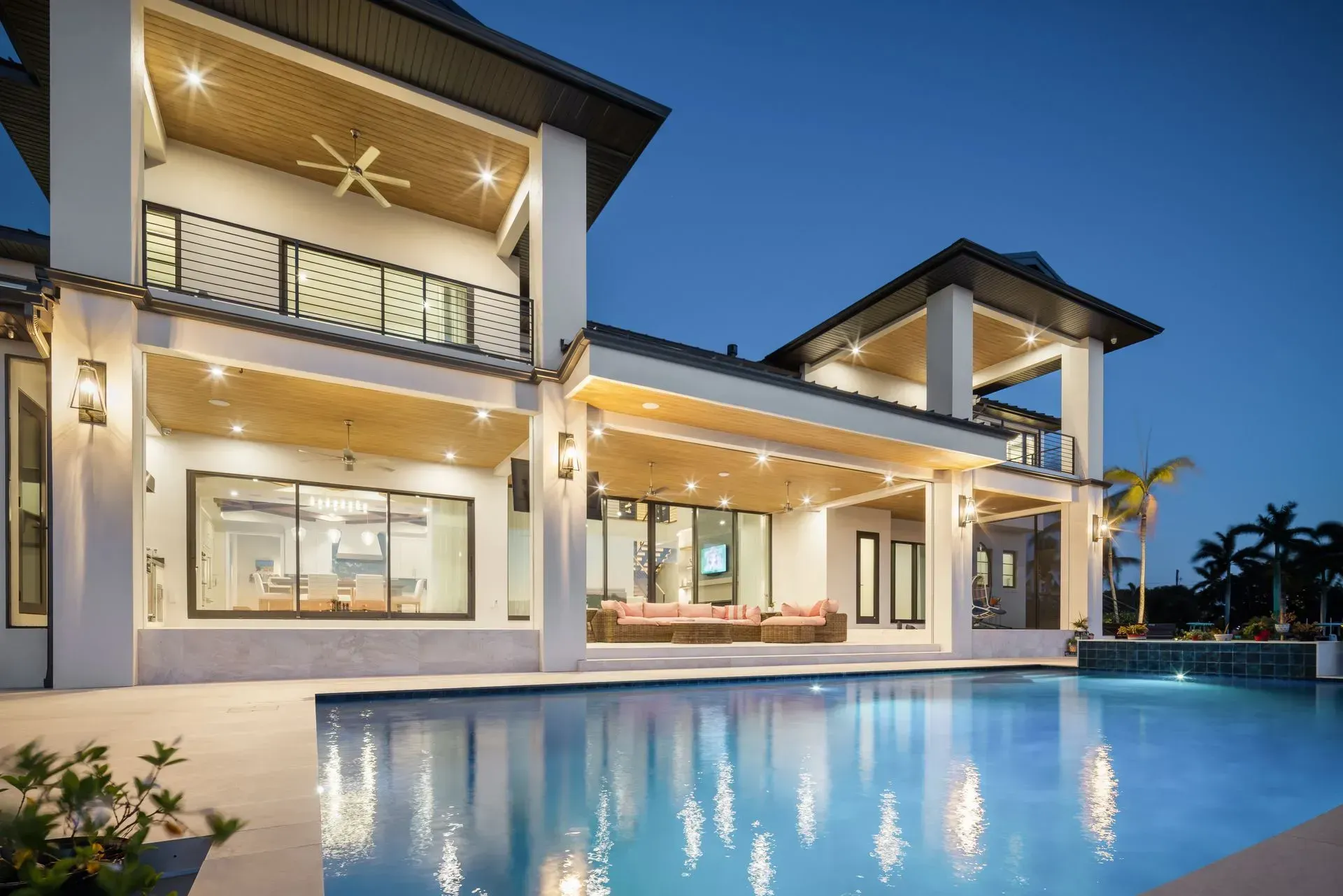 Luxurious modern home with a pool at dusk, lit with warm lights.