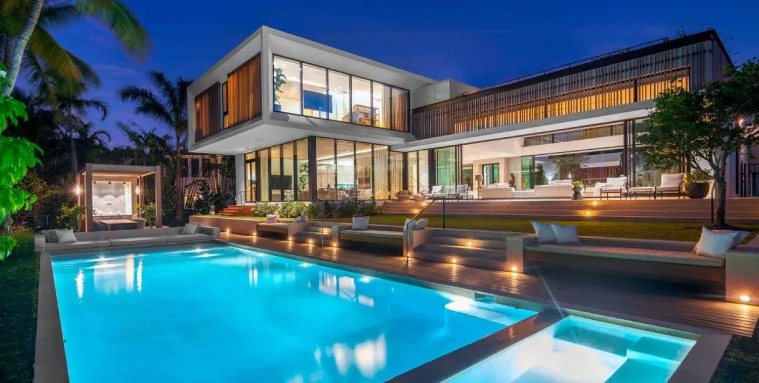 Modern luxury home with a pool illuminated at night.
