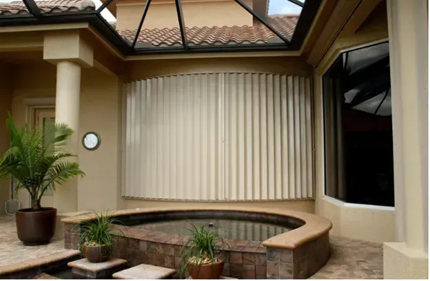 Outdoor spa area with beige hurricane shutters and a round hot tub.