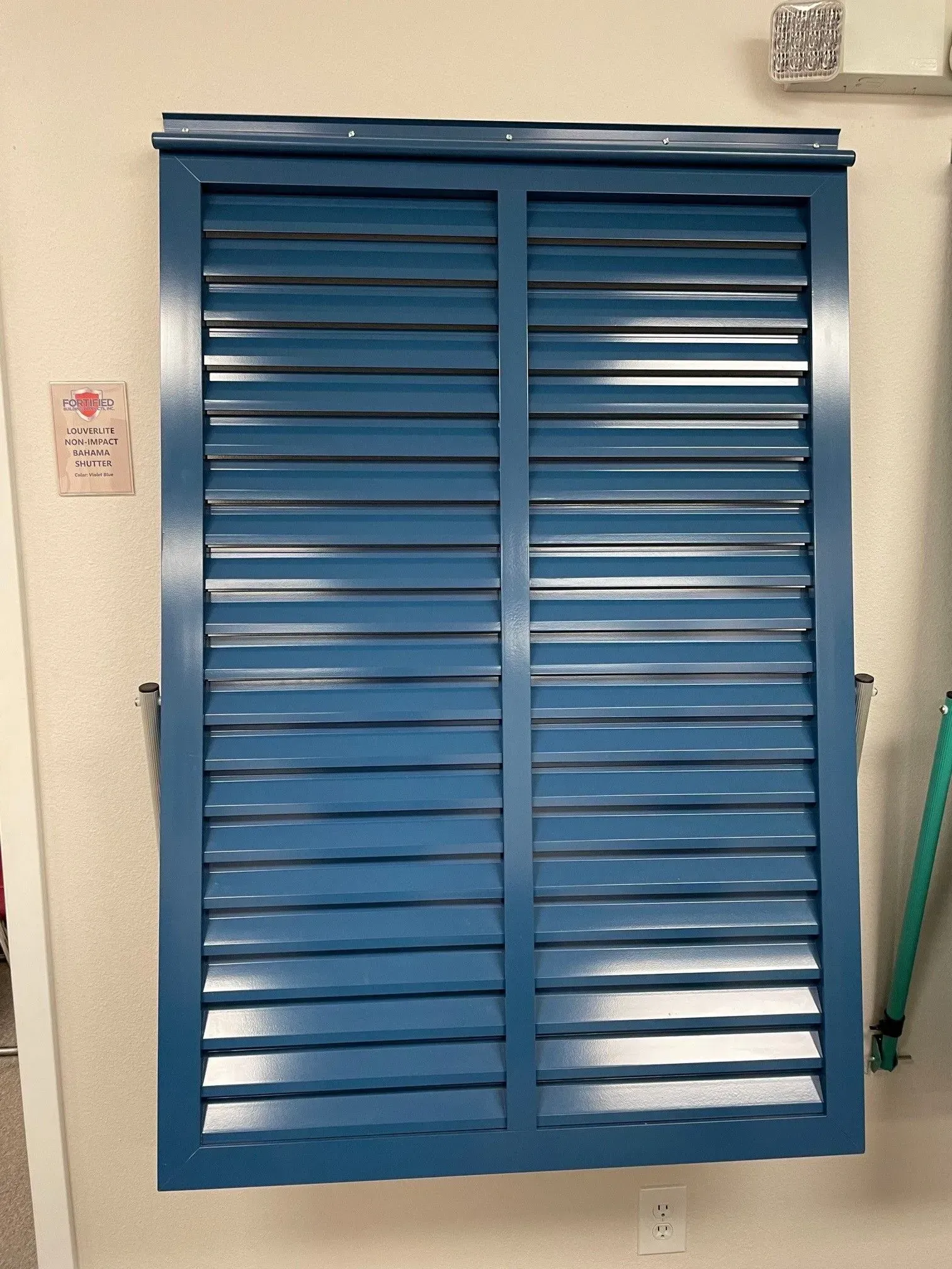 Blue louvered shutters on a light-colored wall.