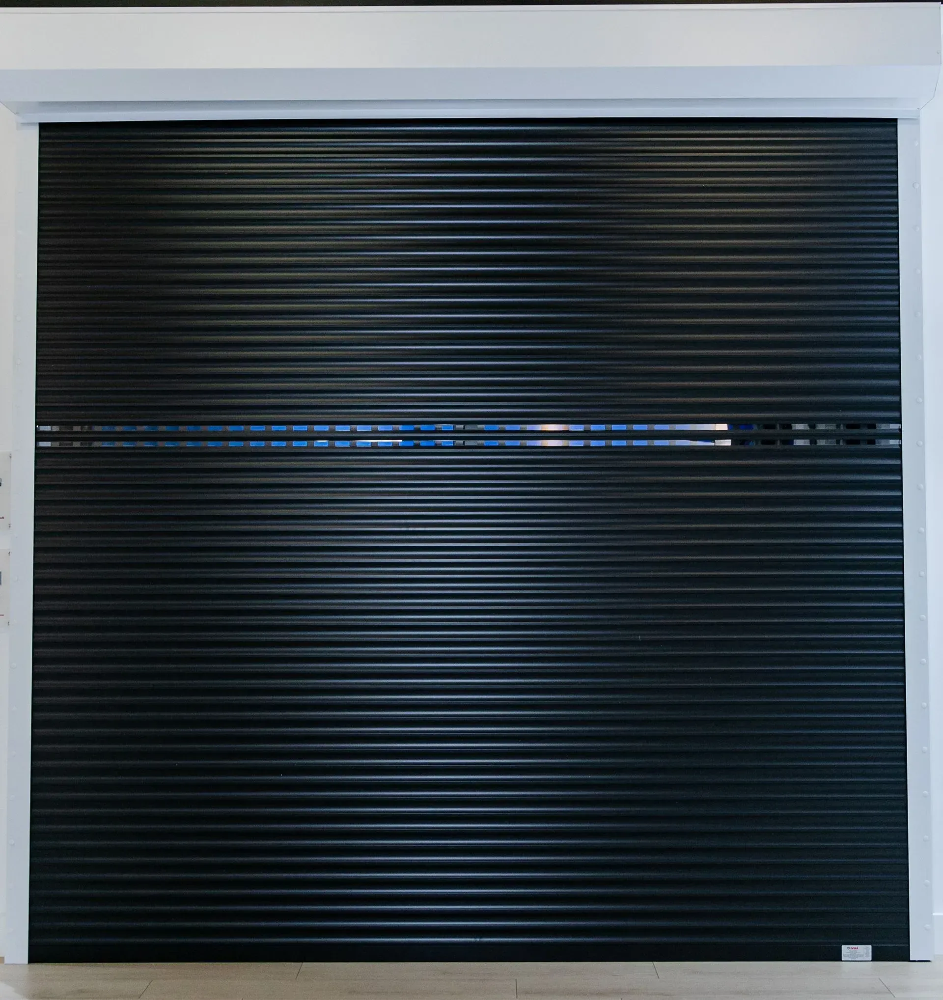 Black horizontal ribbed garage door. A horizontal silver line is embedded in the door.