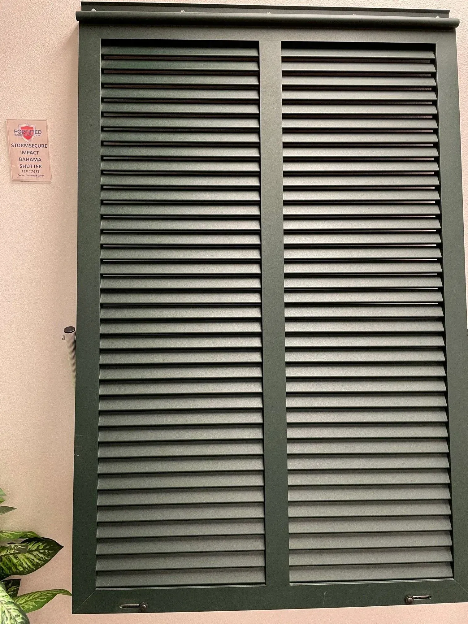 Green louvered shutters on a light-colored wall.
