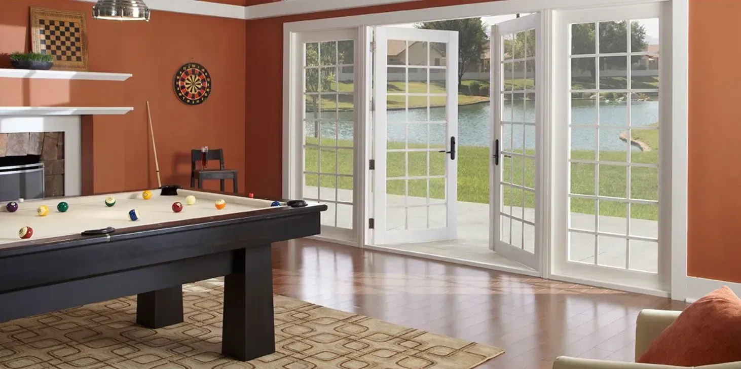 Pool table in a room with a lake view through French doors. The walls are orange.