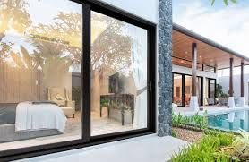 Large sliding glass doors reveal a bedroom. A pool and outdoor patio with a roof are visible.