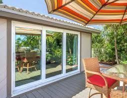 Sliding glass doors open to a patio with wicker chairs and a striped umbrella overhead.