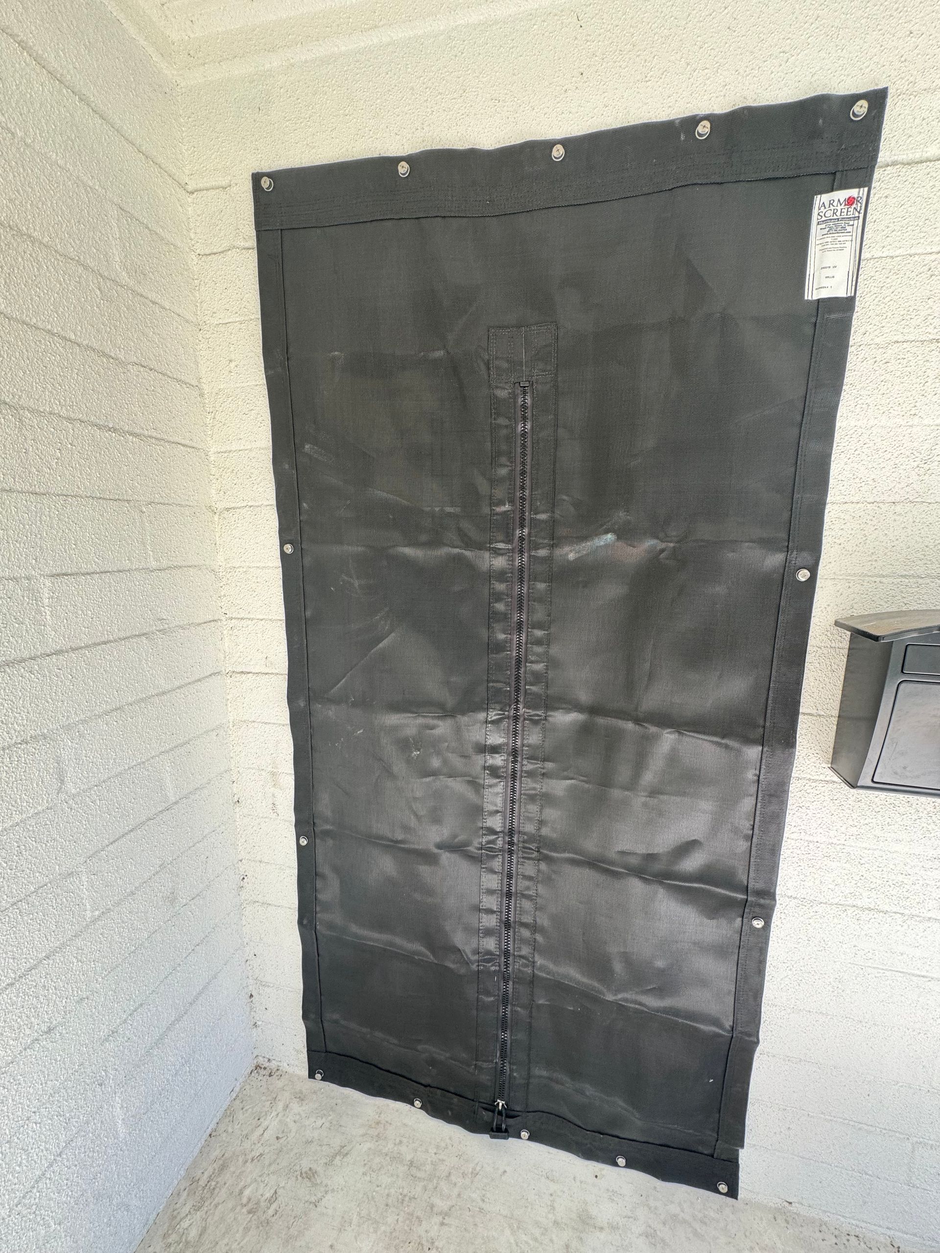 Black fabric door covering an opening in a concrete wall.