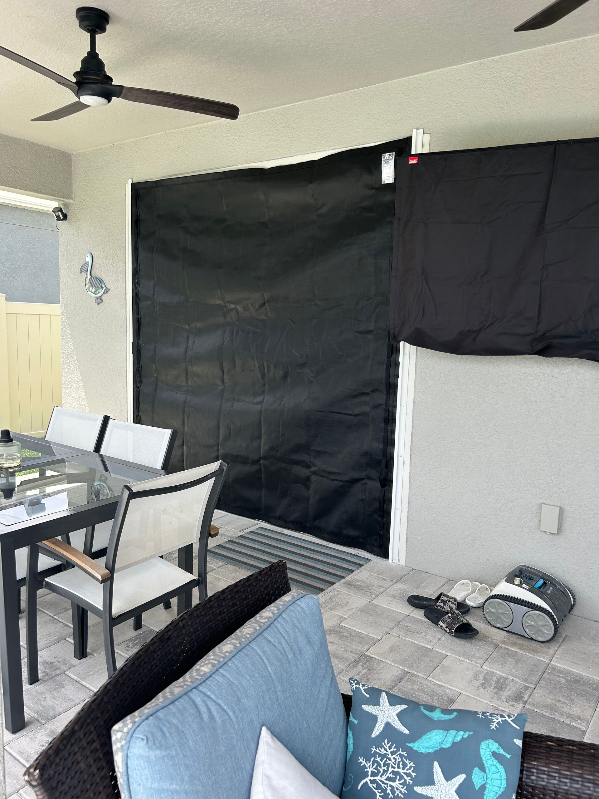 Outdoor patio with black shades, furniture, and ceiling fan.