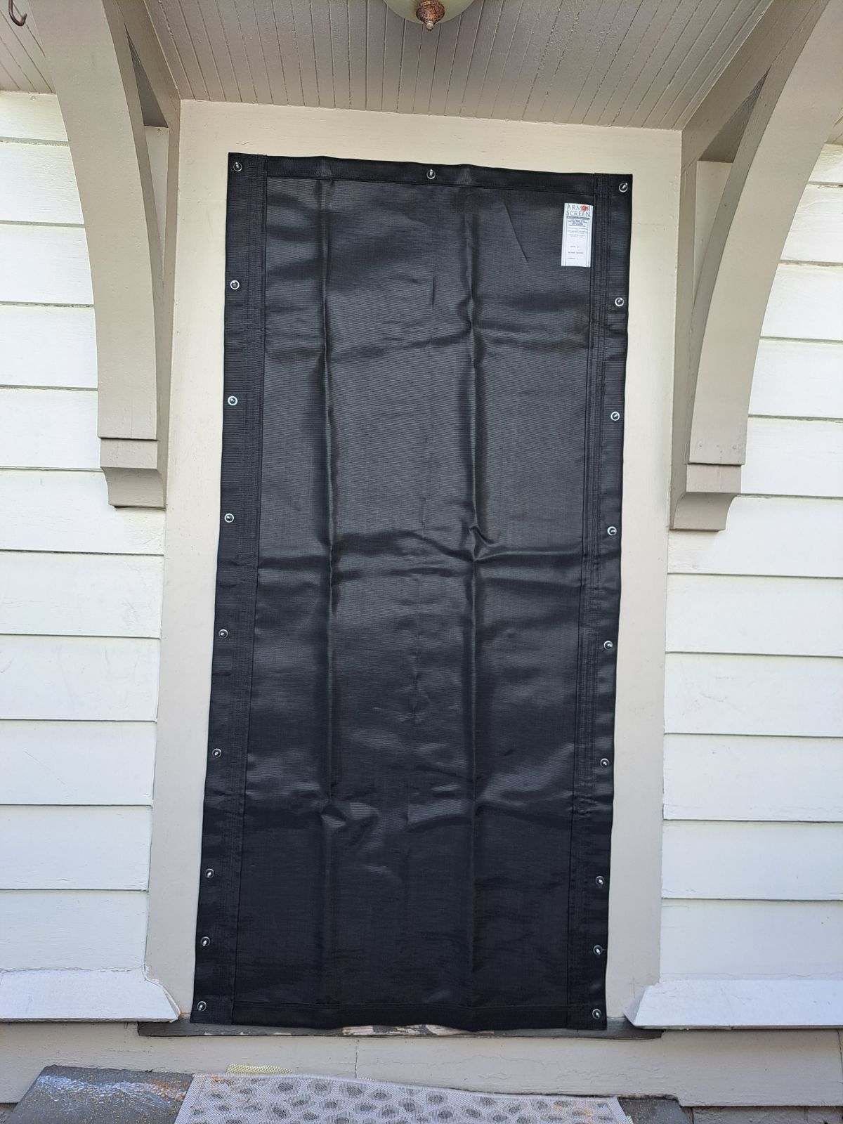 Black mesh door screen attached to a white door frame.