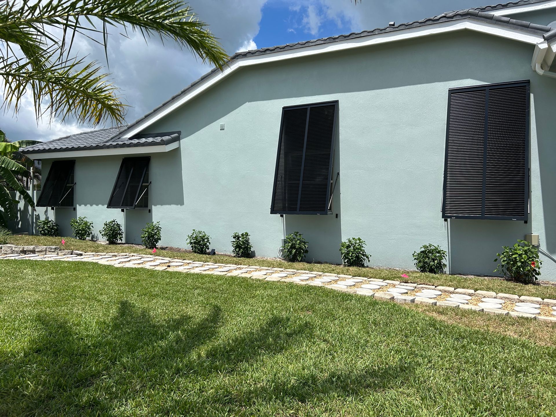 Blue house with black shutters and a stone path in the lawn.