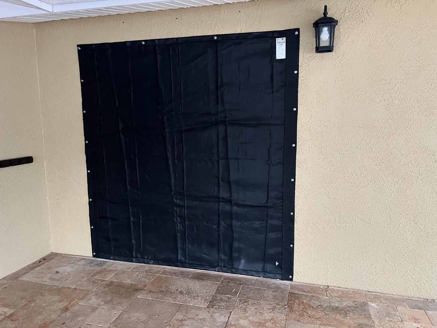 Black fabric covering a doorway on a tan stucco wall. A light fixture is beside the fabric.