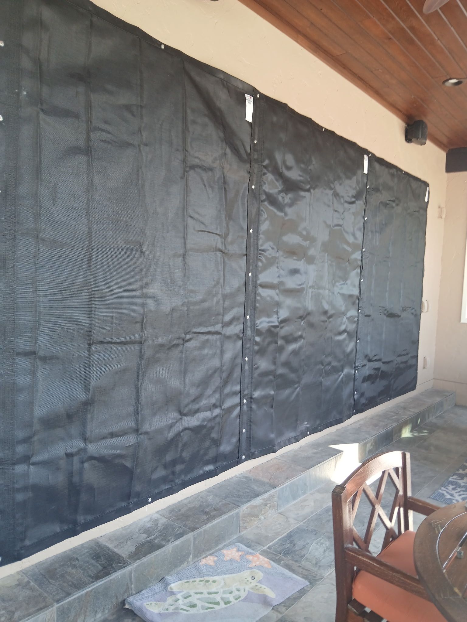 Black mesh screen covering a porch opening, attached to the wall with snaps.