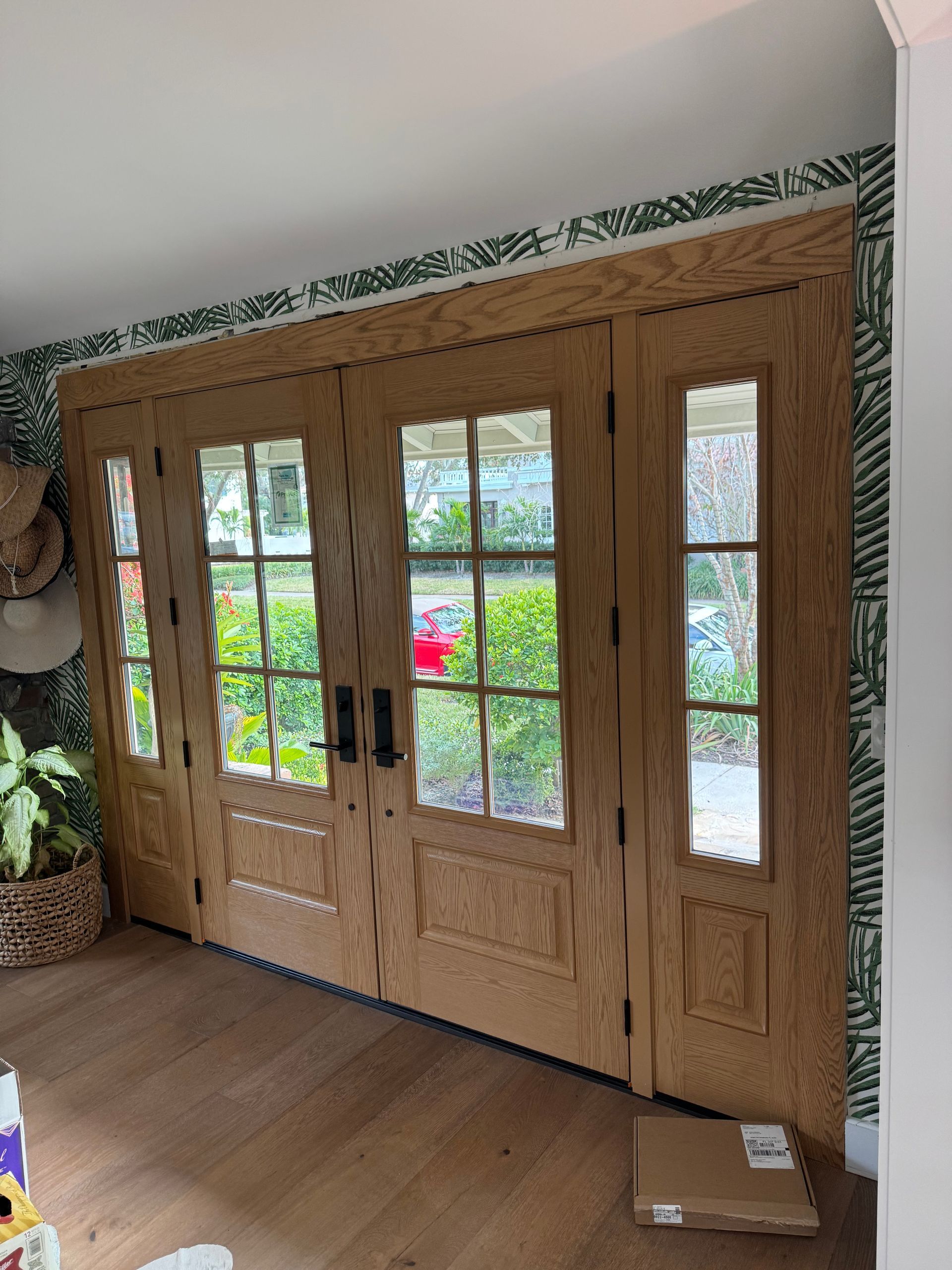 Wooden double doors with glass panels; interior setting with patterned wallpaper and light wood floors.