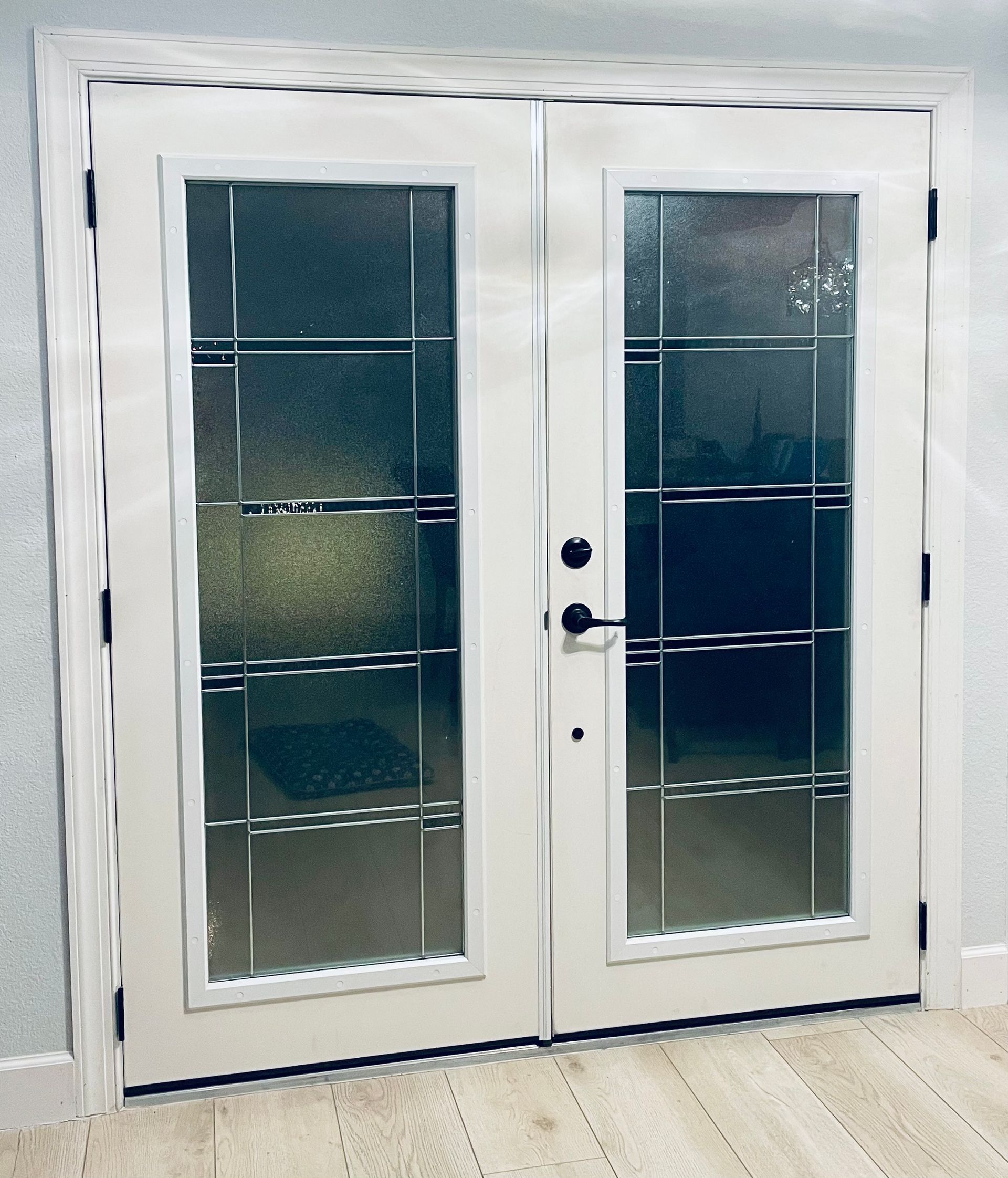 White double doors with frosted glass panels and black handles.