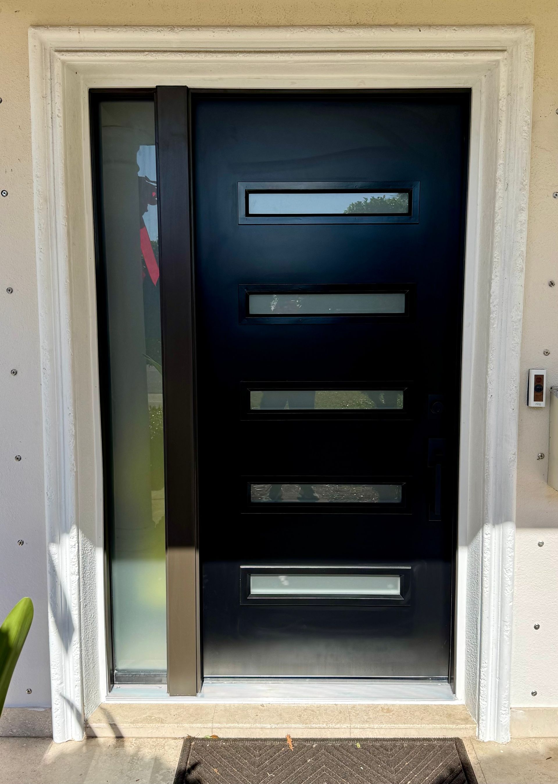 Black modern front door with sidelight and horizontal glass panels.
