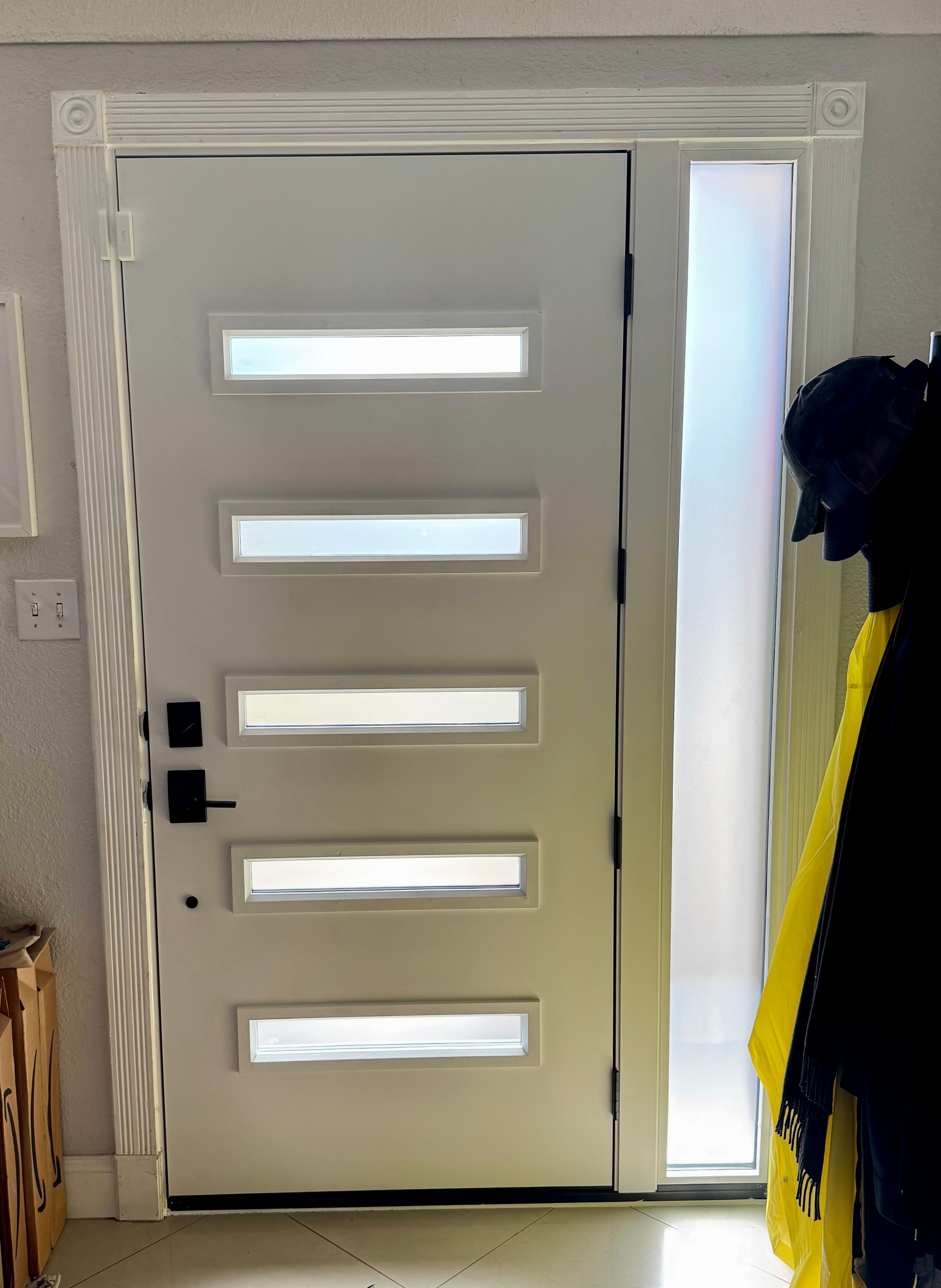 White door with frosted glass panels, next to a sidelight, black door hardware.