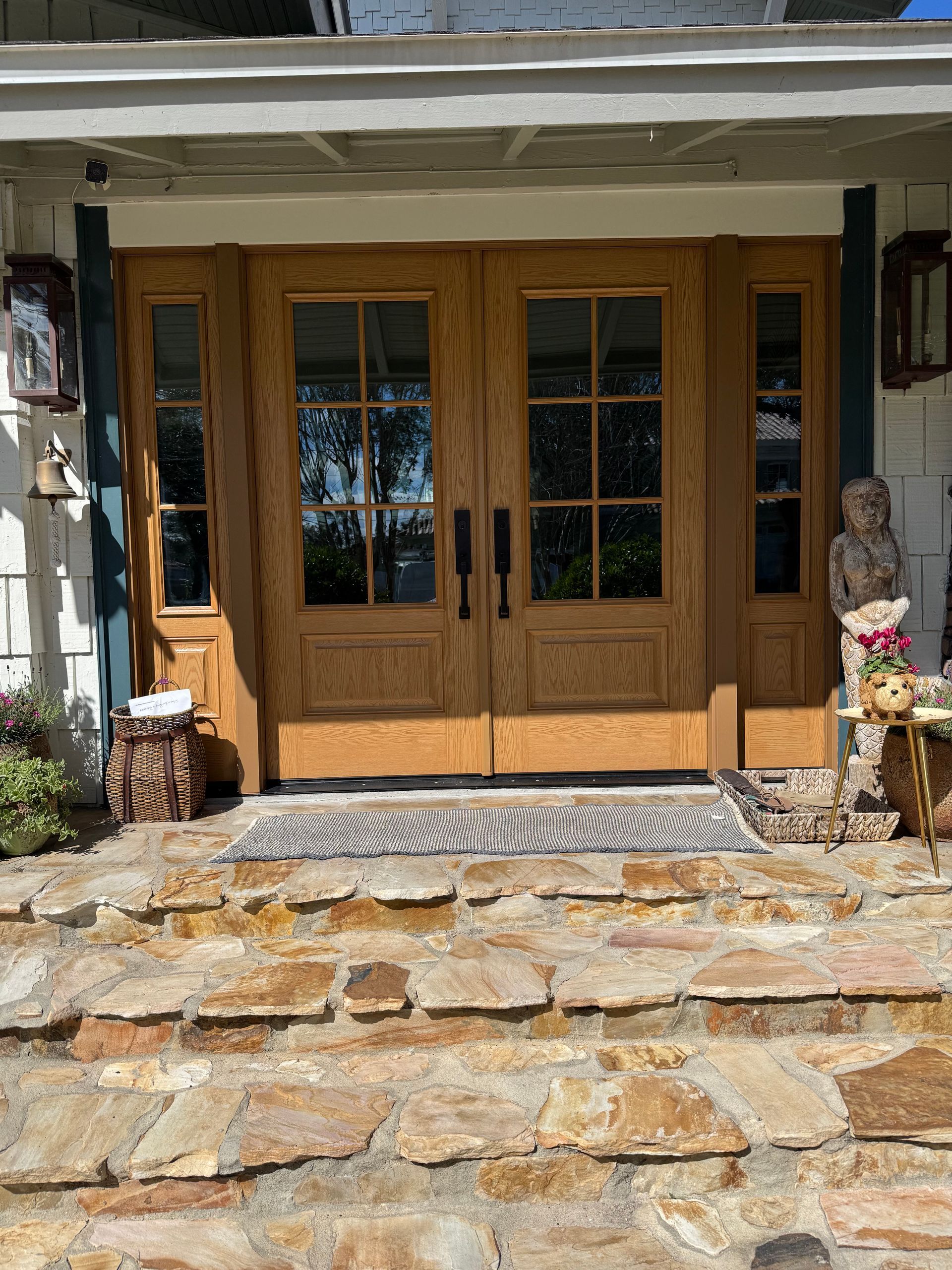 Wooden double doors with glass panels and sidelights on a stone porch, accessed by stone steps.
