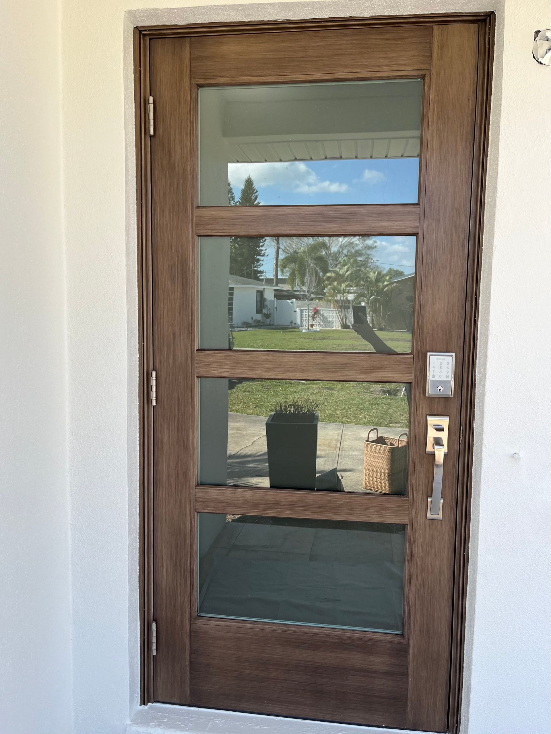 Wooden door with four glass panels, a gold handle, and a smart lock.