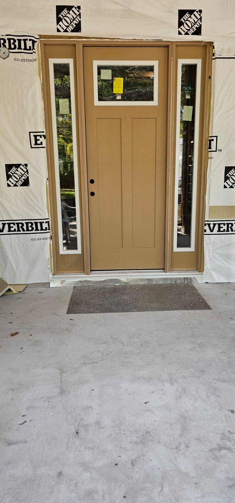Exterior view of a door with sidelights, under construction. Door is brown. Sidelights are clear.