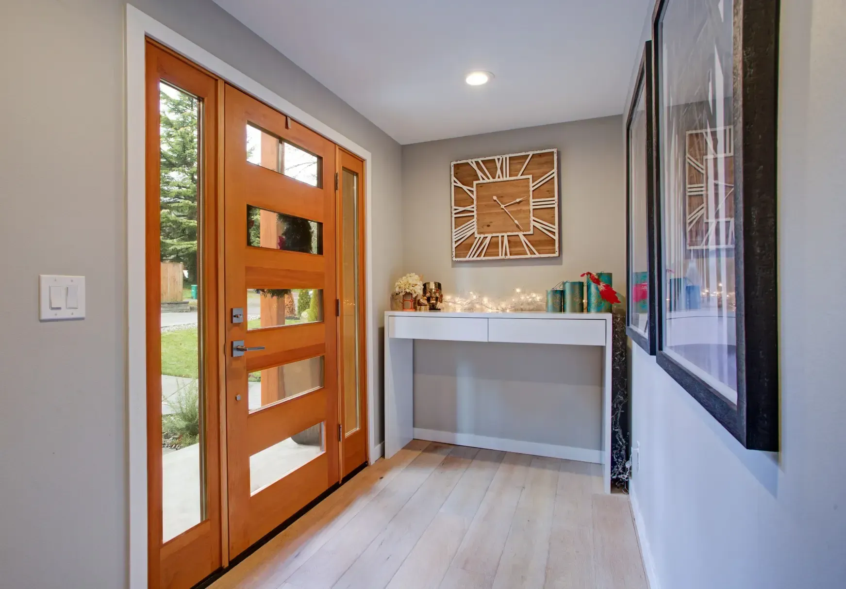 Wooden front door with glass panels; entry hallway with console table and artwork.