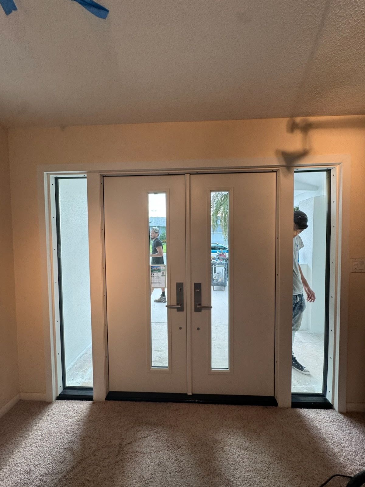 Double white doors with glass panels, flanked by windows. A person walks through one door.