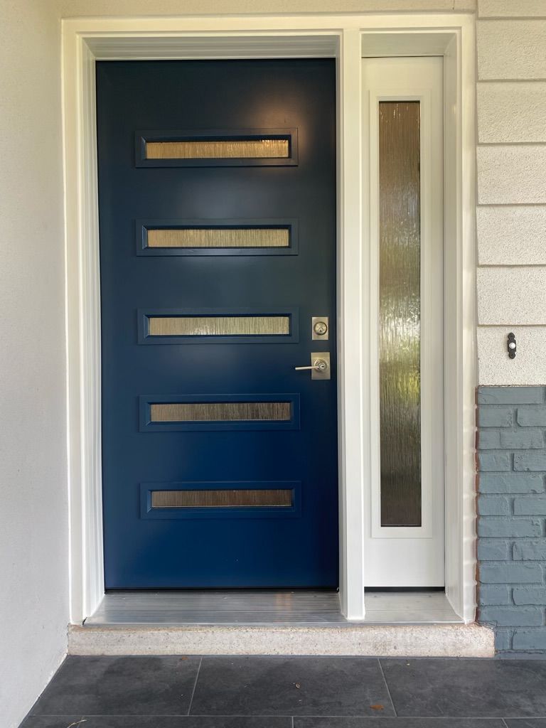 Blue front door with horizontal glass panels, next to a white side window, set in white trim.