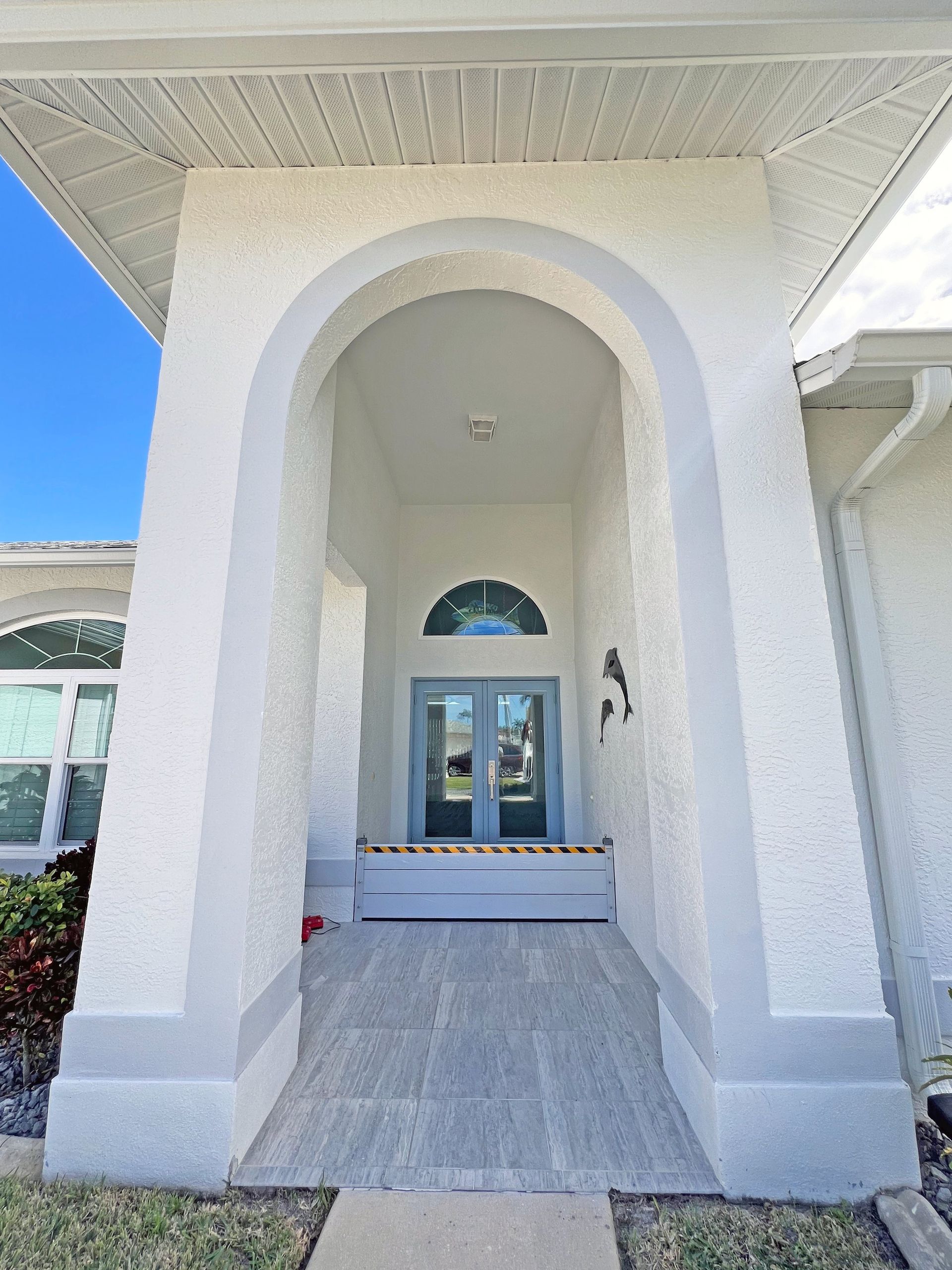 White stucco entryway with arched opening and blue double doors.