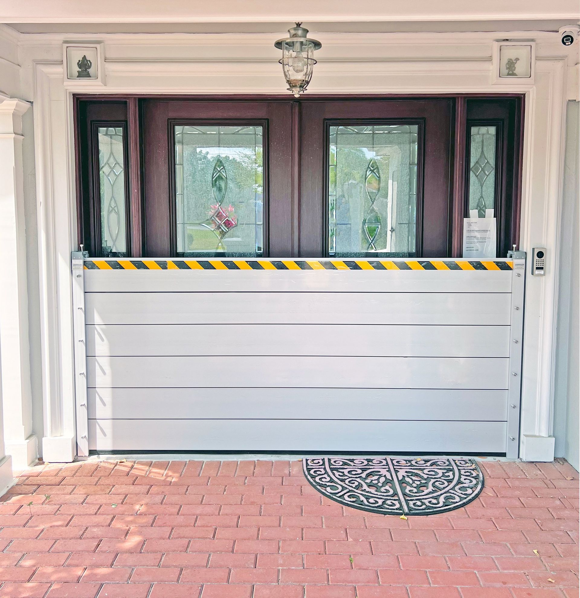 Aluminum flood barrier installed in front of a doorway. Yellow and black striped top, protecting the entrance.