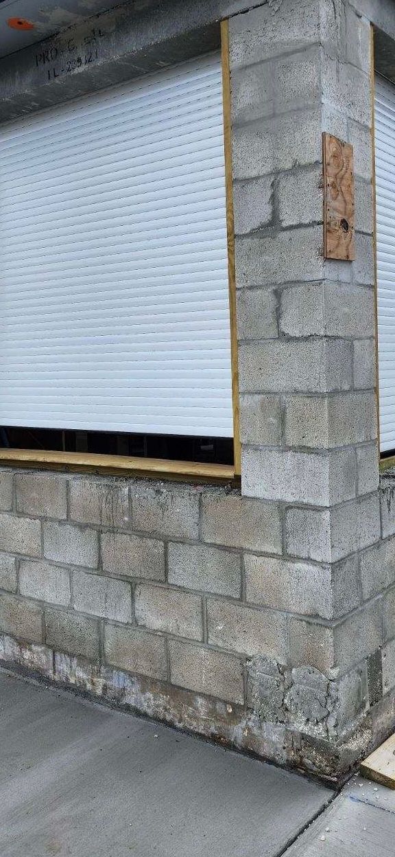 Concrete block structure with a white rollup door, set on a concrete slab.