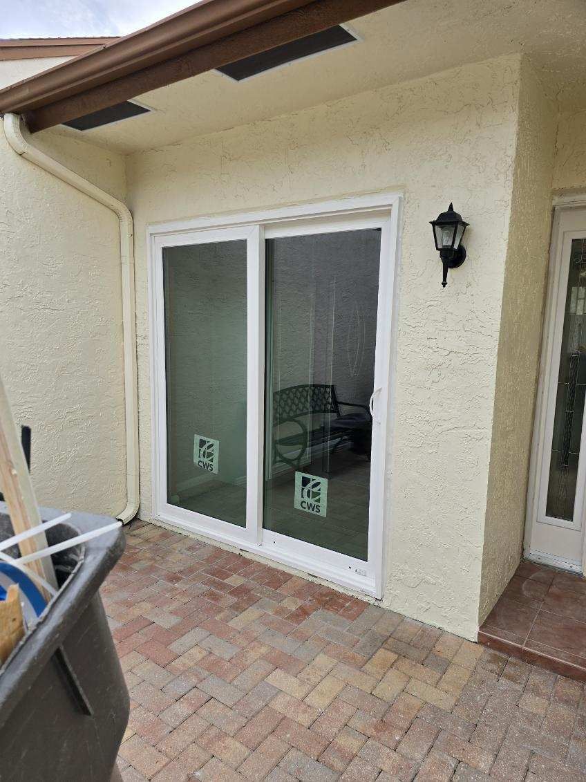 Sliding glass door in an exterior wall, tan stucco, brick patio, black light fixture.