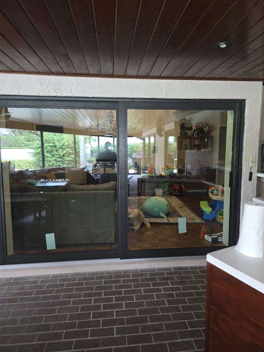 Sliding glass doors with a view of a living room, set in a brick patio, with a wooden ceiling.